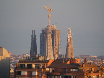 Communications tower in city against sky