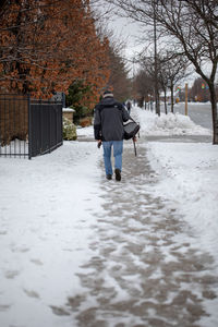 Rear view of man walking on footpath during winter