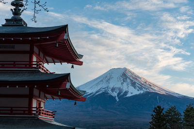 Traditional windmill on snowcapped mountain against sky