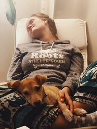 Young woman with dog relaxing on sofa at home