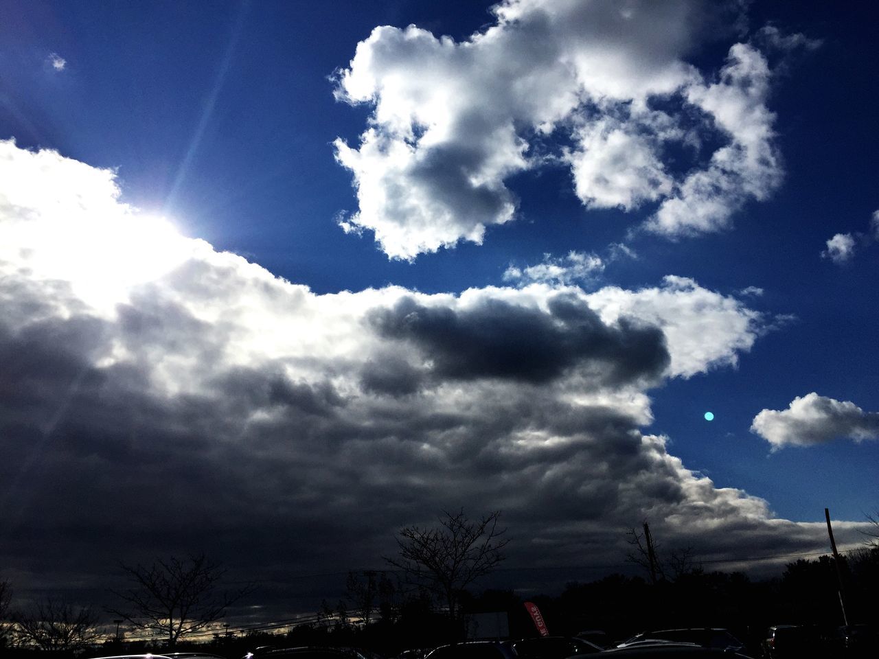 sky, cloud - sky, low angle view, sunbeam, blue, cloudy, cloud, sun, sunlight, beauty in nature, nature, silhouette, scenics, outdoors, no people, cloudscape, transportation, lens flare, day, city