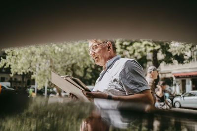 Senior man holding vinyl records at flea market