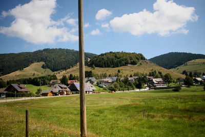 Houses and trees on field against sky