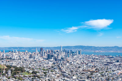 High angle view of city buildings against blue sky