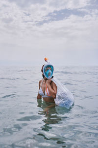 Man holding umbrella in sea against sky