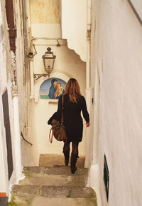 Rear view of woman moving down on steps