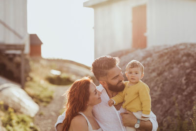 Smiling parents looking at baby girl while standing on archipelago during sunny day