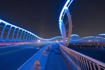 Light trails on bridge against sky at night