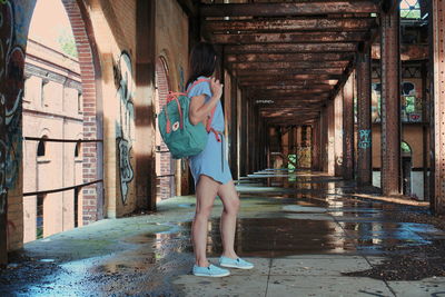 Side view of woman standing by building