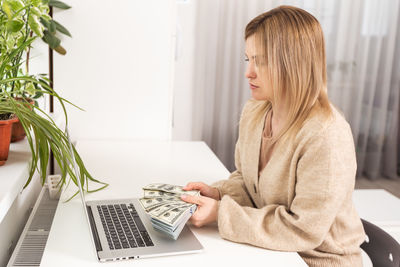 Young woman using laptop while sitting on table at home
