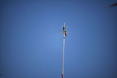 Low angle view of telephone pole against clear blue sky