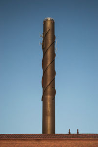 Low angle view of smoke stack against clear blue sky