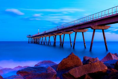 Pier on sea against blue sky