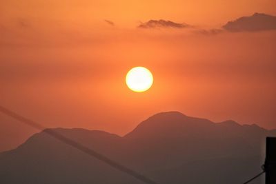 Scenic view of silhouette mountains against orange sky