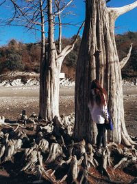 Rear view of woman standing by tree trunk