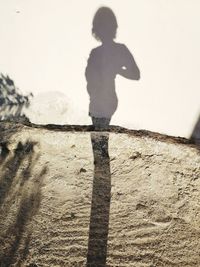 Shadow of boy standing against wall