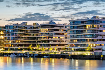 Buildings by river against sky