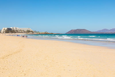 Scenic view of beach against clear blue sky