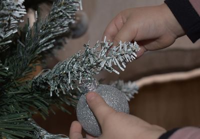 A four years old child who explores the magic of christmas by decorating the tree 