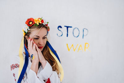 Portrait of young woman standing against wall