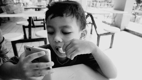 Close-up of boy using mobile phone at cafe