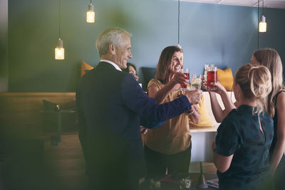 Happy business colleagues celebrating success with drinks in office cafeteria during party