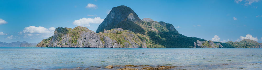 Panoramic view of sea and mountains against blue sky