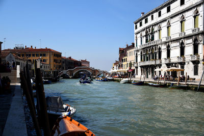 Boats in canal amidst buildings in city against sky