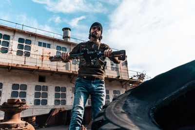 Low angle view of young man photographing against sky