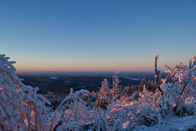 Scenic view of snow covered landscape against clear sky during sunset