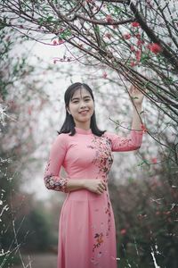 Portrait of young woman standing against trees