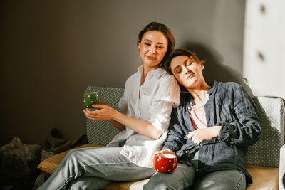 Portrait of young woman using mobile phone while sitting at home