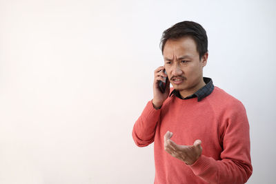 Mid adult man using smart phone against white background