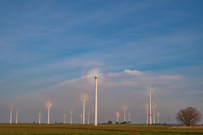 Wind turbines on field against sky