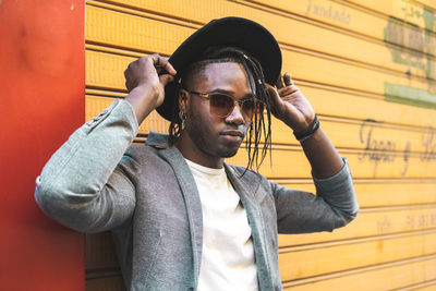 Portrait of young man wearing sunglasses against wall