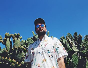 Low angle view of young man standing against clear blue sky