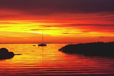 Silhouette sailboats in sea against orange sky