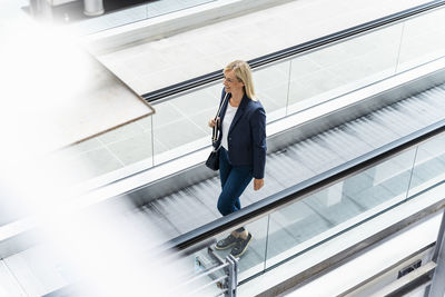 Smiling businesswoman standing on moving walkway