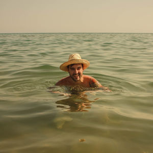 Portrait of happy man swimming in sea during sunset