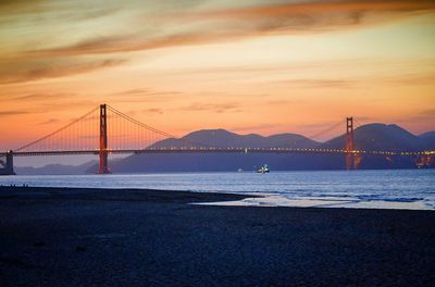 Suspension bridge over sea during sunset