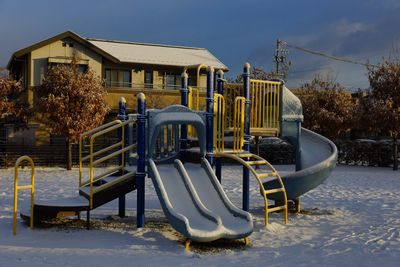 Snow covered slide on playing field at park
