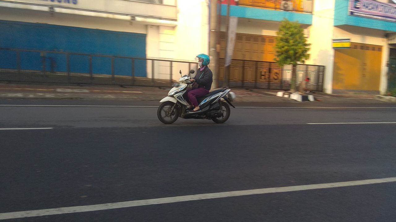 MAN RIDING SCOOTER ON STREET