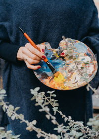 Midsection of woman holding artist palette