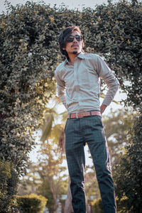 Portrait of a young man standing against trees