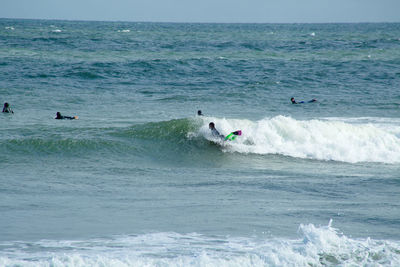 People surfboarding on sea