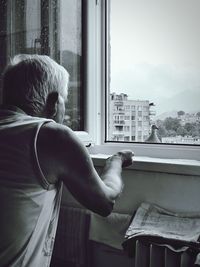 Rear view of man looking through window