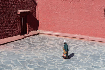 HIGH ANGLE VIEW OF MAN WALKING ON FOOTPATH