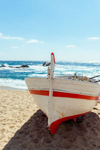 Deck chairs on beach against sky