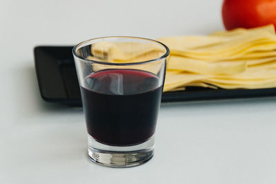 Close-up of red wine glass and uncooked pasta in plate on table