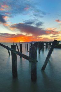 Pier over sea against sky during sunset